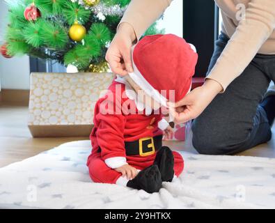 Un bambino eccitato a natale seduto accanto a un regalo avvolto Foto Stock