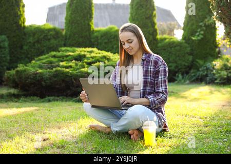 Donna che usa un notebook su un prato verde nel parco Foto Stock