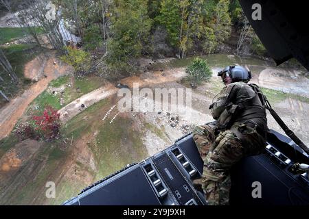 Ovest, North Carolina, Stati Uniti. 4 ottobre 2024. Derick Bauman, ingegnere di volo della B Company, 2nd Battalion, 238th Aviation Regiment, Ohio Army National Guard osserva gli ostacoli dalla rampa posteriore di un elicottero CH-47 Chinook mentre atterra in un campo per distribuire cibo, acqua e altri rifornimenti alle comunità della Carolina del Nord occidentale dopo l'uragano Helene, ottobre. 4, 2024. Le unità della Guardia Nazionale di 17 stati hanno risposto alle aree colpite dalla tempesta e hanno partecipato alla distribuzione di cibo e acqua, alla ricerca e al salvataggio, alla rimozione dei detriti a Foto Stock