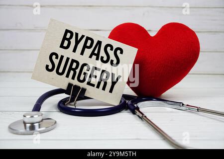 Bypass Surgery text message on paper card with stethoscope on wooden background Stock Photo