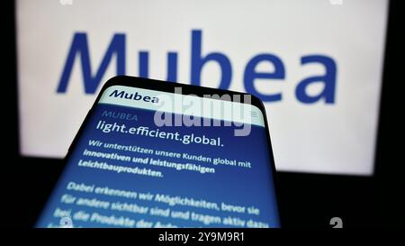 In questa illustrazione fotografica, un telefono cellulare con il sito web dell'azienda automobilistica tedesca Muhr und Bender KG (Mubea) è visto davanti al logo aziendale. Foto Stock