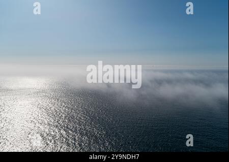 Una morbida nebbia sorge dall'oceano mentre il sole inizia ad illuminare l'orizzonte. Foto Stock