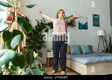 Una giovane e bella donna taglia si allunga le braccia mentre si gode un momento sereno a casa. Foto Stock