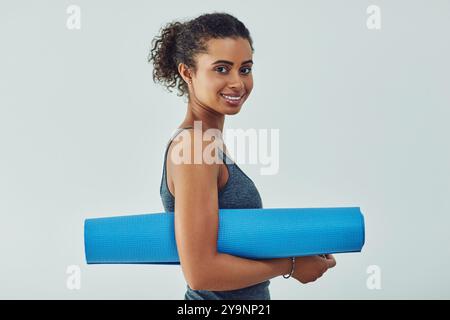 Donna, stuoia per yoga e casa per muro in ritratto per iniziare la giornata con benessere, sorriso e sicurezza. Ragazza, felice e pronta per l'allenamento dei pilates, orgoglio Foto Stock