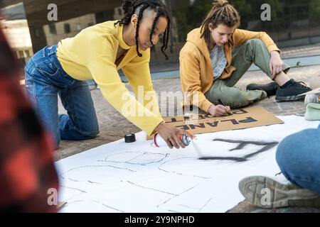 Giovani e diversi attivisti lavorano insieme per creare striscioni e cartelli di protesta. Image cattura la collaborazione, la creatività e l'impegno dei giovani Foto Stock