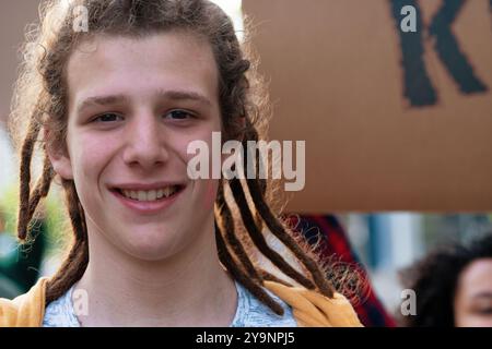 Ritratto ravvicinato di un giovane allegro con dreadlock, che indossa abiti casual. L'immagine rappresenta la cultura giovanile, la diversità e l'espressione di sé Foto Stock