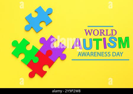 Testo del World Autism Awareness Day e pezzi colorati del puzzle su sfondo giallo, vista dall'alto Foto Stock