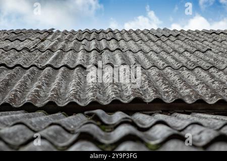 Lenzuola di amianto grigie su un tetto di casa, vista panoramica con cielo blu Foto Stock