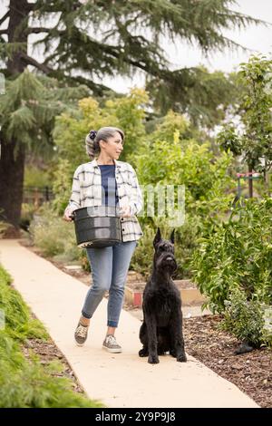 Donna e cane che camminano attraverso il giardino Foto Stock