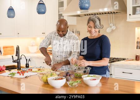 Una coppia che si diverte a ridere insieme mentre preparano il cibo Foto Stock