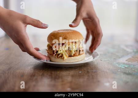 Mani che raccolgono hamburger con carne e spada Foto Stock