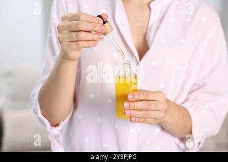 Giovane donna che prende tintura CBD all'interno, primo piano Foto Stock