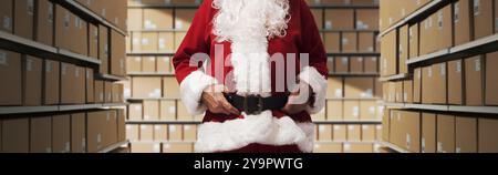 Babbo Natale in piedi nel corridoio del magazzino e controllare le scatole di consegna con i regali di Natale Foto Stock