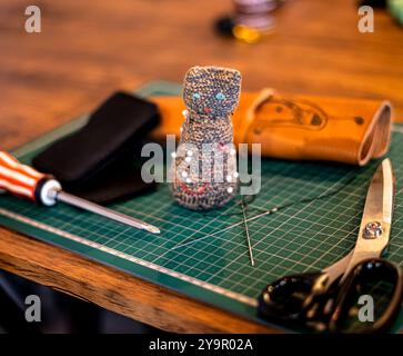 Strumento da cucire per lavori ad ago e forbici su un tappeto verde e un tavolo in legno Foto Stock