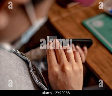 Le mani del maestro cucire i prodotti in pelle fatti a mano le mani femminili collegano le parti creando accessori in pelle di qualità processo di lavorazione in pelle Foto Stock