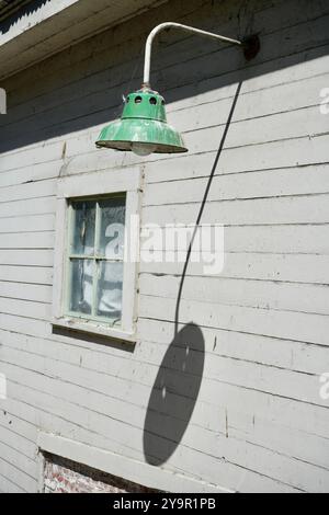 Lampada elettrica vintage per esterni con ombra su un edificio in legno sull'isola di Alcatraz. Foto Stock