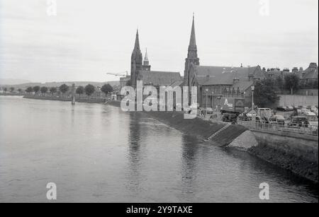 1976, vista storica sul lungofiume di Inverness, Scozia, Regno Unito e sulle guglie della Old High Church, la Free Church of Scotland e la St Columba High, accanto al fiume Ness, che scorre da Loch Ness. Foto Stock