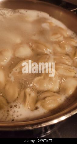 Gli gnocchi a forma di cuore cucinano in acqua bollente. Foto mobile verticale Foto Stock