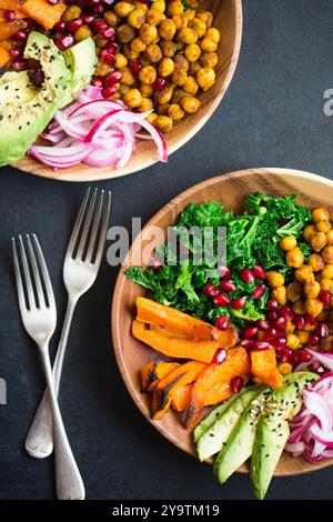 Calda insalata invernale con zucca arrostita, ceci piccanti, cavoli verdi al vapore, avocado e cipolla rossa sottaceto in ciotole di legno. Foto Stock