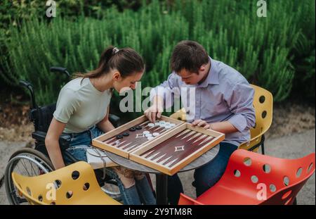 I bambini con sindrome di Down e le ragazze in sedia a rotelle si godono il backgammon all'aperto Foto Stock