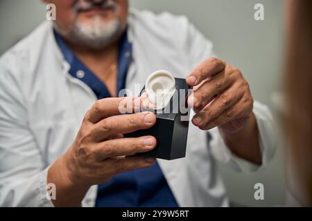 Medico di sesso maschile che dimostri un apparecchio acustico al paziente Foto Stock