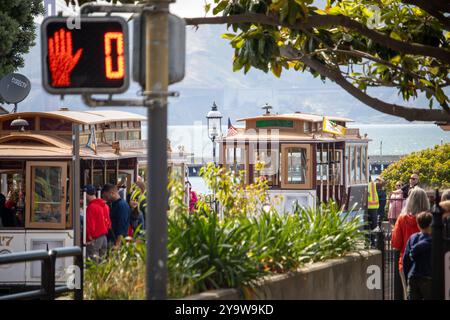 Alla fine della linea, vivace scena urbana di San Francisco con le iconiche funivie Powell e Hyde e i turisti si sono riuniti vicino a un segnale stradale. Foto Stock