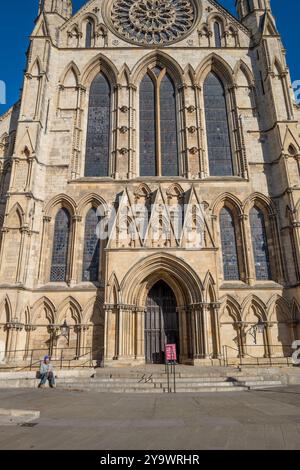 Uomo seduto sulla pietra scolpita seduto all'ingresso della cattedrale di York in una soleggiata mattinata d'autunno, York, Yorkshire, Inghilterra. Foto Stock