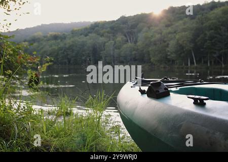 Il kayak blu si appoggia sulla costa del lago di montagna accanto all'acqua scintillante Foto Stock