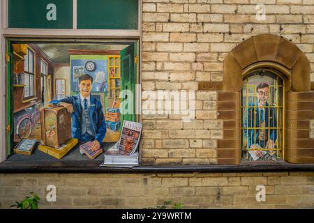 Murale dipinto a mano di un pacco maschile e di un addetto alla biglietteria alla stazione ferroviaria di Knaresborough con la rivista Yorkshire Living. Foto Stock