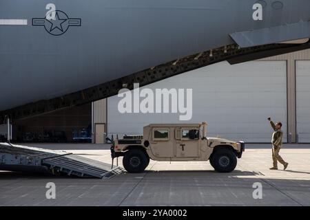 Albert Rein, assegnato al 137th Airlift Squadron, 105th Airlift Wing, guida un veicolo a ruote multiuso ad alta mobilità su un C-17 Globemaster III sulla Hancock Field Air National Guard base a Syracuse, NY, 9 ottobre 2024. Le guardie nazionali dell'aviazione e dell'esercito di New York sono state recentemente mobilitate per sostenere le comunità in Florida colpite dall'uragano Milton. (Foto della Guardia Nazionale dell'Esercito degli Stati Uniti di Joseph Liggio) Foto Stock