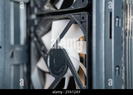 Vista ravvicinata della ventola di raffreddamento del computer, che mostra le pale e il telaio. La ventola è parzialmente coperta di polvere, a indicare l'utilizzo. Lo sfondo è BL Foto Stock