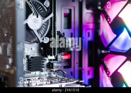 Vista ravvicinata di un moderno case per computer che mostra componenti interni come un raffreddatore CPU, una scheda madre e ventole RGB. L'illuminazione colorata crea una V Foto Stock