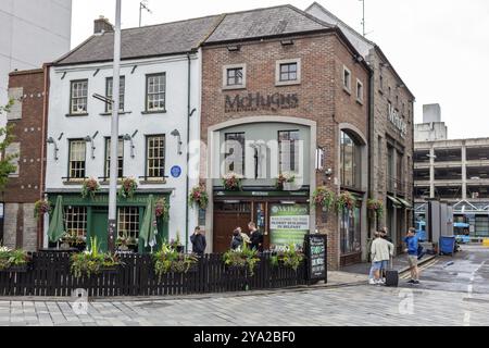 Storico edificio pub con ingressi decorati con fiori e passanti sul marciapiede, Belfast Foto Stock