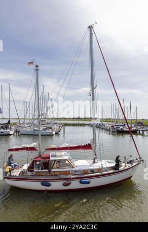 Barca a vela che scivola sulle acque calme con una bandiera tedesca issata sull'albero, Ruegen, Hiddensee Foto Stock