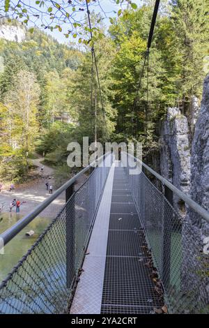 Un lungo ponte sospeso che conduce attraverso un sentiero roccioso nella foresta, circondato dalla natura, Klobenstein Foto Stock