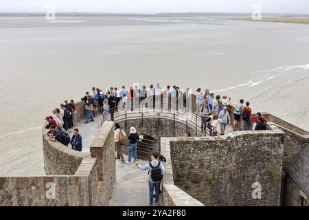 Un gruppo di persone si trova su una piattaforma panoramica che si affaccia sul mare ed è circondato da mura storiche, le Mont-Saint-Michel Foto Stock