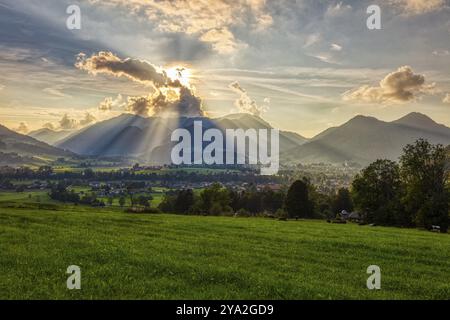 I raggi del sole si infrangono attraverso le nuvole su un vasto paesaggio montano con prati verdi, Ruhpolding Foto Stock