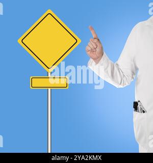 Medico in camice bianco con stetoscopio e oftalmoscopio in tasca, tenendo il pollice e indicando un cartello Foto Stock