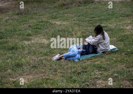 Germania, Berlino, 15.09.2024, domenica pomeriggio a Mauerpark, coppia sul prato sul pendio, Reading, Europa Foto Stock