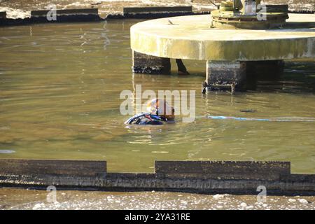 Il casco di un subacqueo guarda fuori da un bacino in un impianto di depurazione Foto Stock