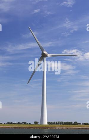 Turbina eolica di fronte al cielo blu con nuvole all'IJsselmeer nei Paesi Bassi, Noordoostpolder, Flevoland. Turbina eolica davanti al cielo blu con Foto Stock