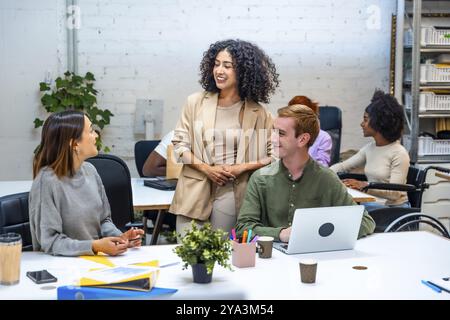 Tre diverse donne e colleghi di sesso maschile che parlano distratti in una moderna sala di coworking Foto Stock