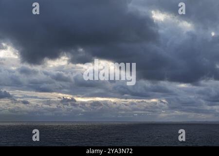 Alba con nuvole scure e un po' di luce che si infrangono sul Mare di Norvegia Foto Stock