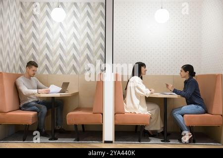 Dipendenti di uffici multietnici che lavorano in cabine di co-working moderne Foto Stock