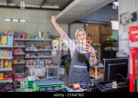 Una donna allegra negoziante si impegna felicemente con i clienti in un piccolo negozio Foto Stock