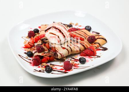 Gelato fresco in Crêpe decorato con bacche miste e sciroppo al cioccolato Foto Stock