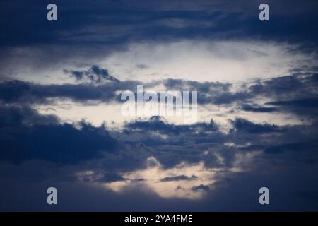 Un cielo spettacolare pieno di nuvole scure al crepuscolo, che cattura un sorprendente contrasto tra luce e ombra in un'atmosfera tranquilla. Foto Stock