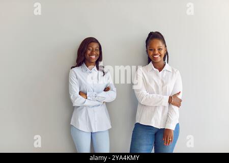 Amici afroamericani, impiegati d'ufficio, donne che sorridono in posa al muro, dipendenti allegri e felici Foto Stock