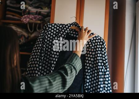 Donna che sceglie un blazer a pois dal suo armadio Foto Stock