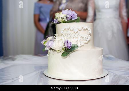 Elegante torta nuziale su più livelli decorata con fiori freschi e design intricato. Foto Stock